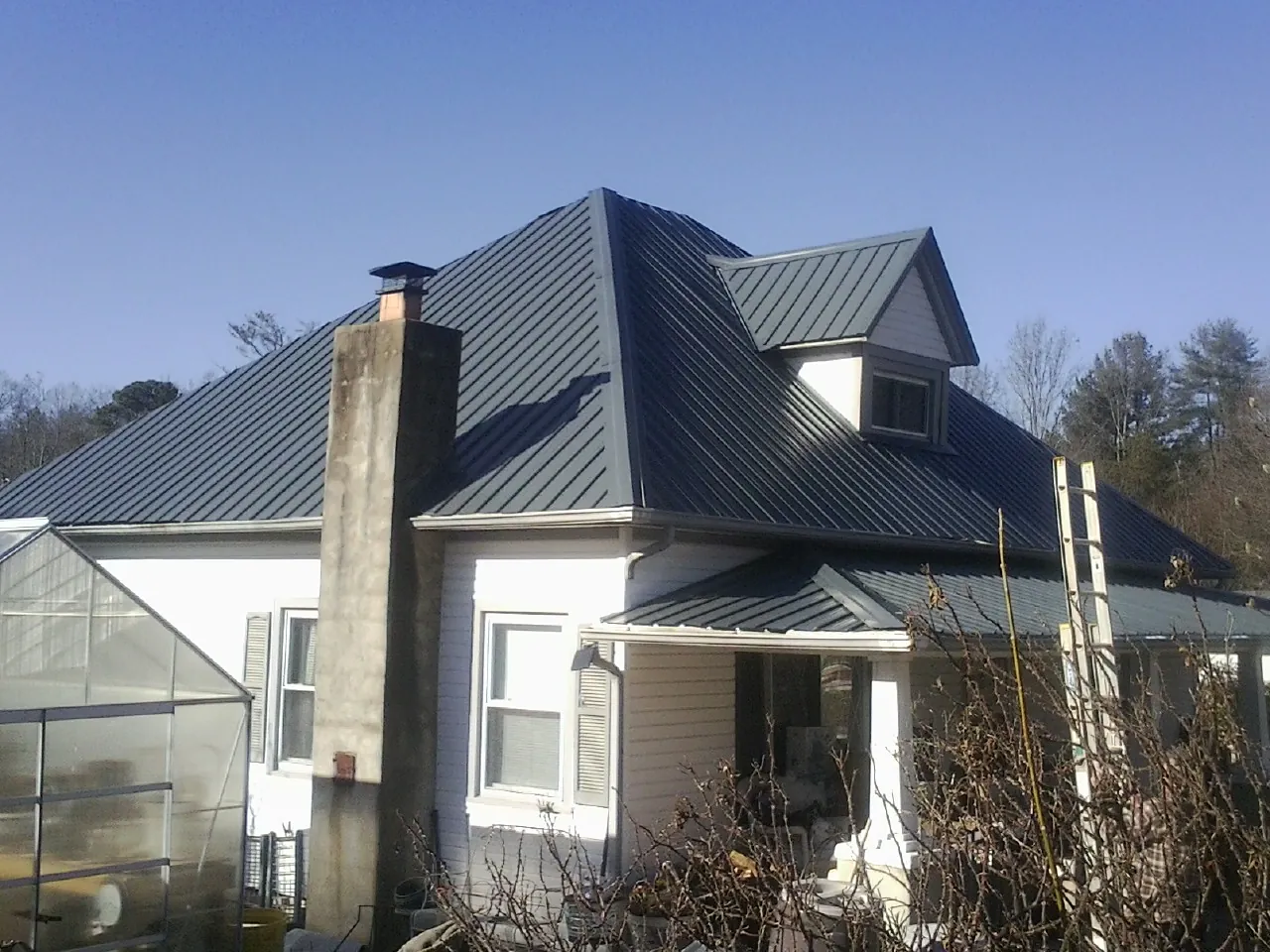 Dark blue standing seam metal roof on a white farmhouse with dormer — Slate & Tile Roof Repair by Roofing Brothers in South Portland