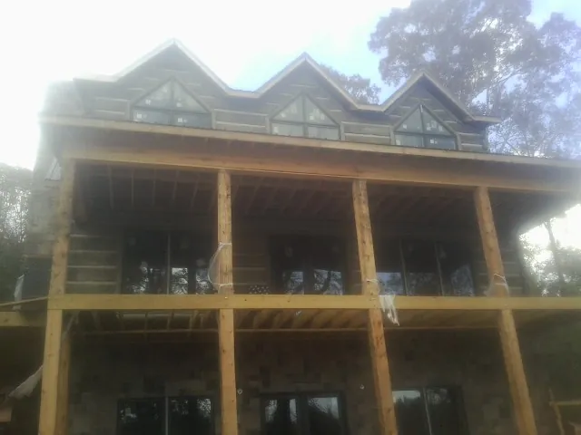 Dormers and porch framing on a large log home under construction — Roof Coating work by our crew in South Portland