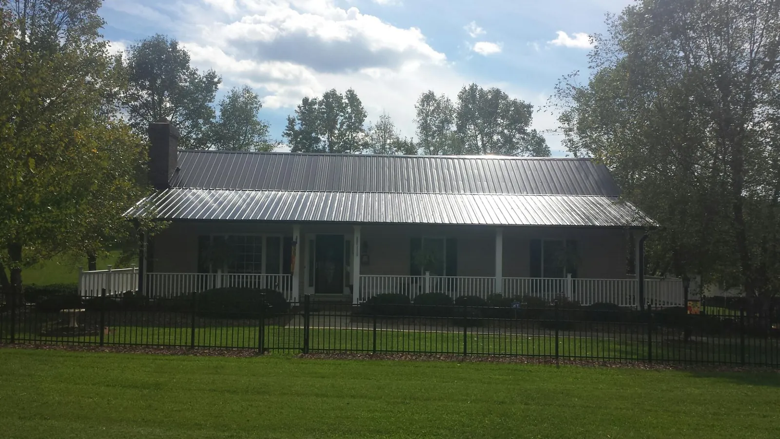 Gray metal roof on a brick ranch with a full width front porch — Gutter Guard Installation work by our crew in South Portland