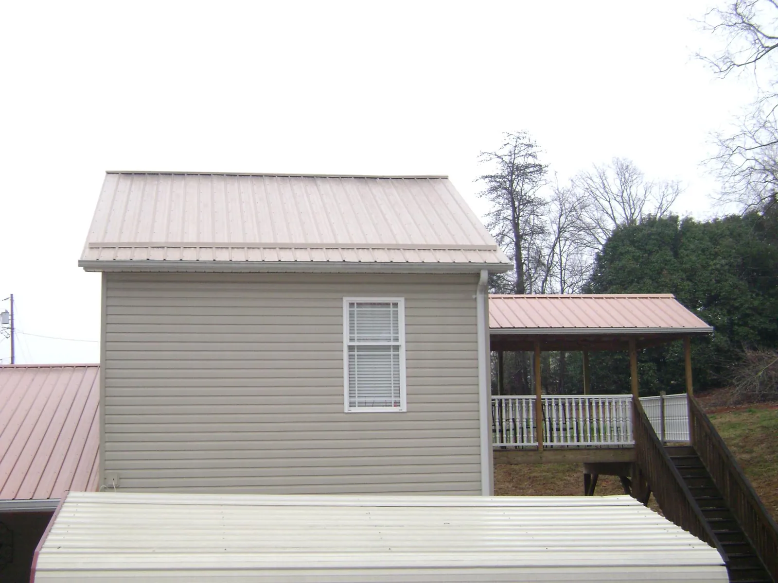 Tan metal roofs on a two story addition and attached porch, from a Roof Replacement job in South Portland