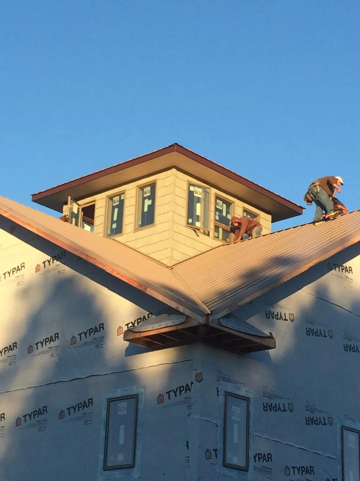 Roofers working around a rooftop cupola on a new metal roof at sunset — Roof Waterproofing in South Portland by Roofing Brothers